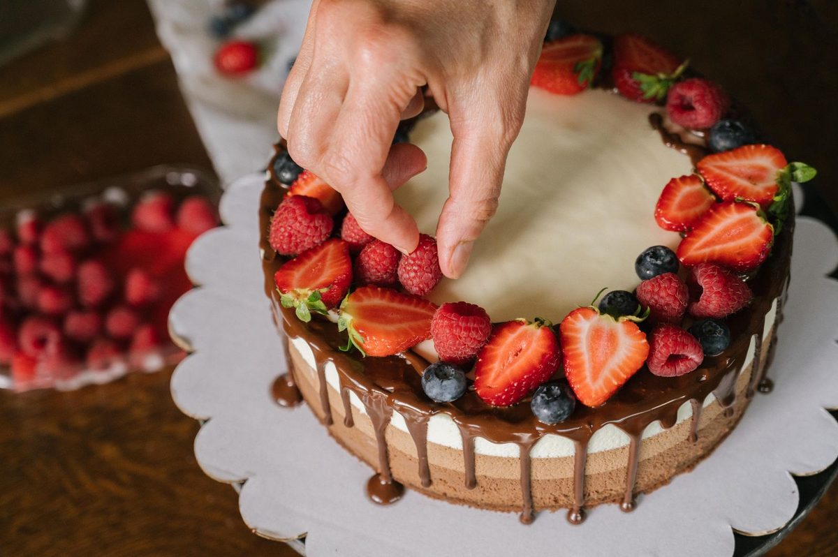 Baker decorating a celebration cake with fresh berries