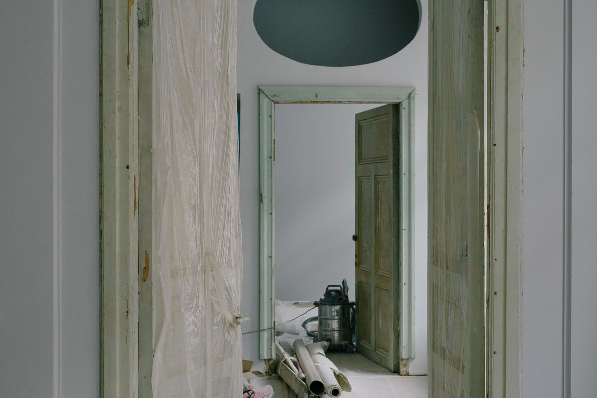 A room mid-renovation, stripped back and dust-sheeted