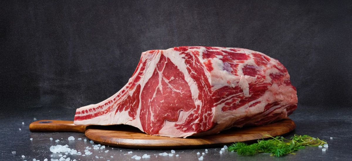 A beautifully marbled rib of beef on a wooden board