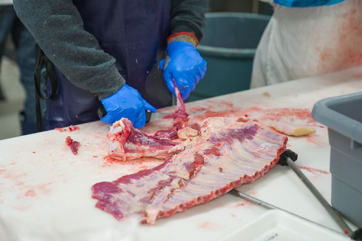 A butcher cutting meat behind the counter