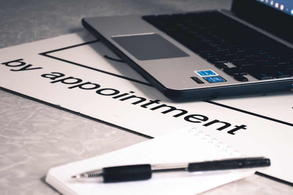 A by appointment sign next to a pen on a desk