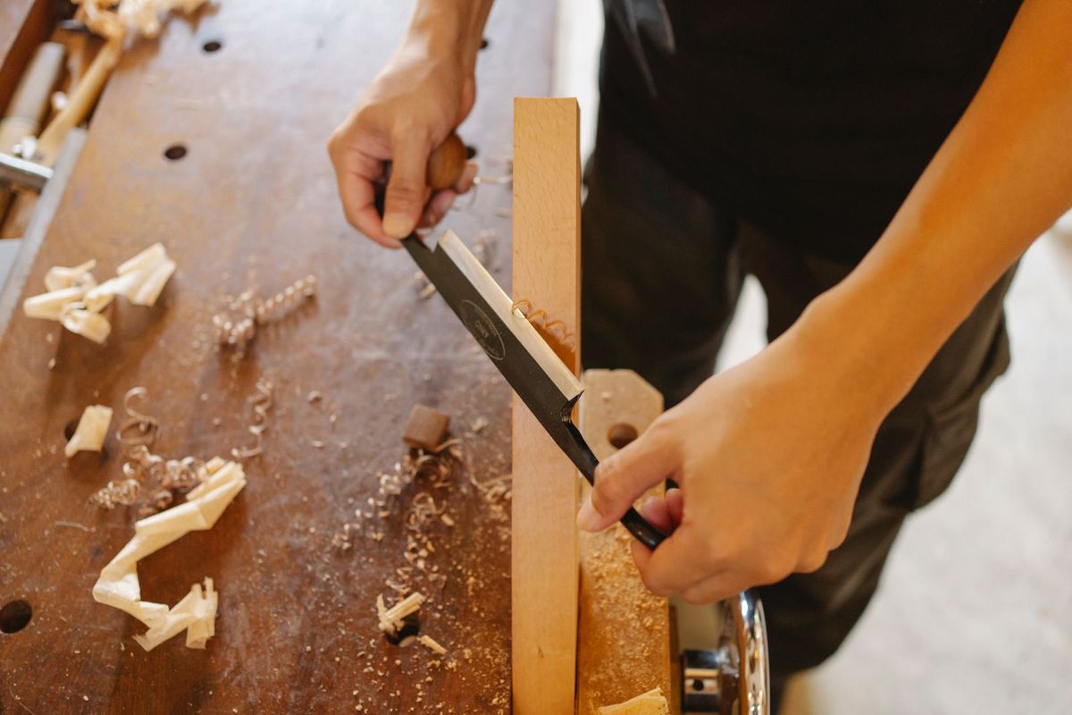 A carpenter measuring and marking a piece of wood with tools
