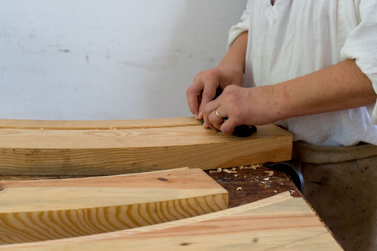 A carpenter working wooden boards to fit