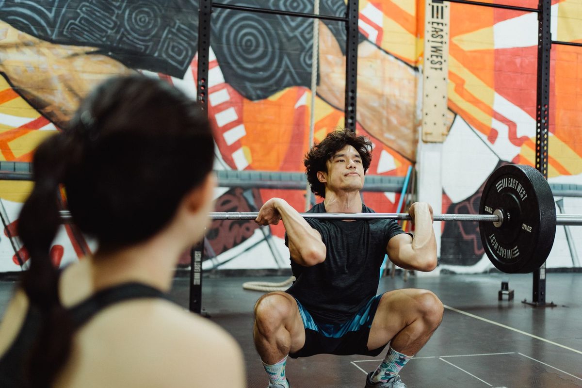 Coach guiding a member through a barbell lift in a studio