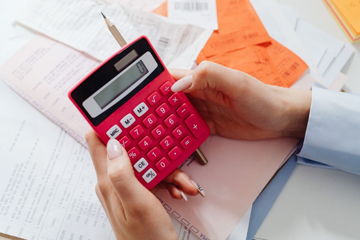 Person working out a budget with a calculator and paperwork