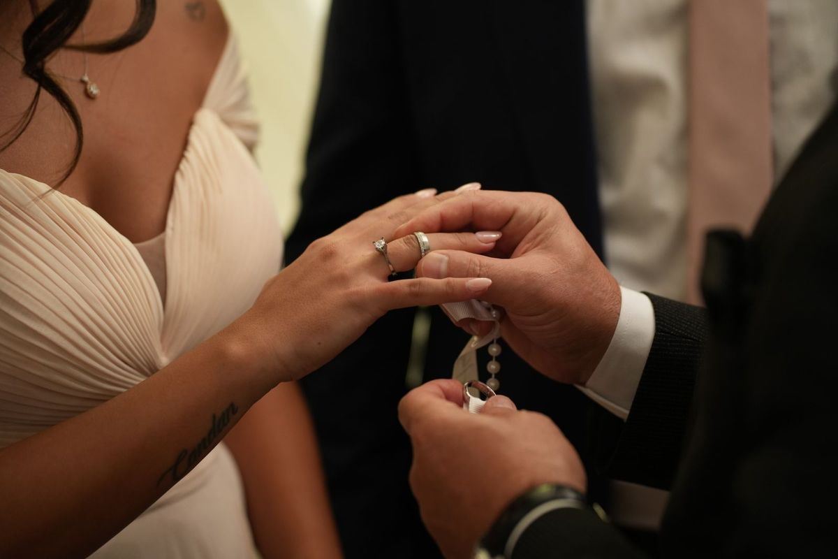 A groom placing a ring on a bride's finger