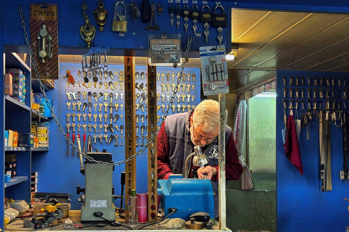 A locksmith cutting keys in a workshop full of keys
