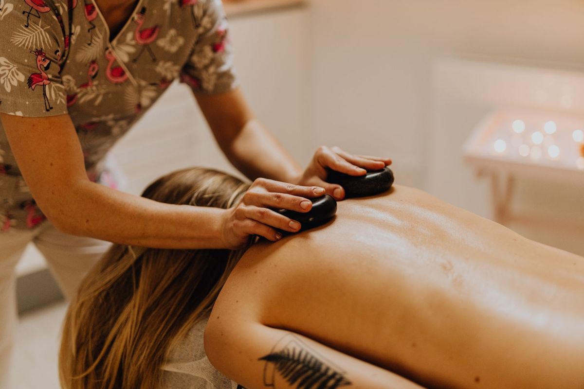 Client receiving a hot stone massage in a warm spa room