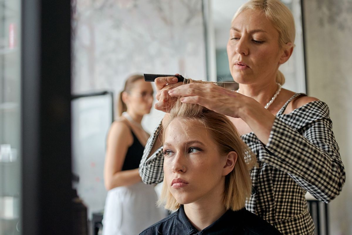 A hairdresser styling a client's hair at home