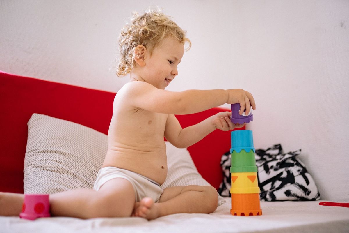 A young child happily playing with colourful building blocks