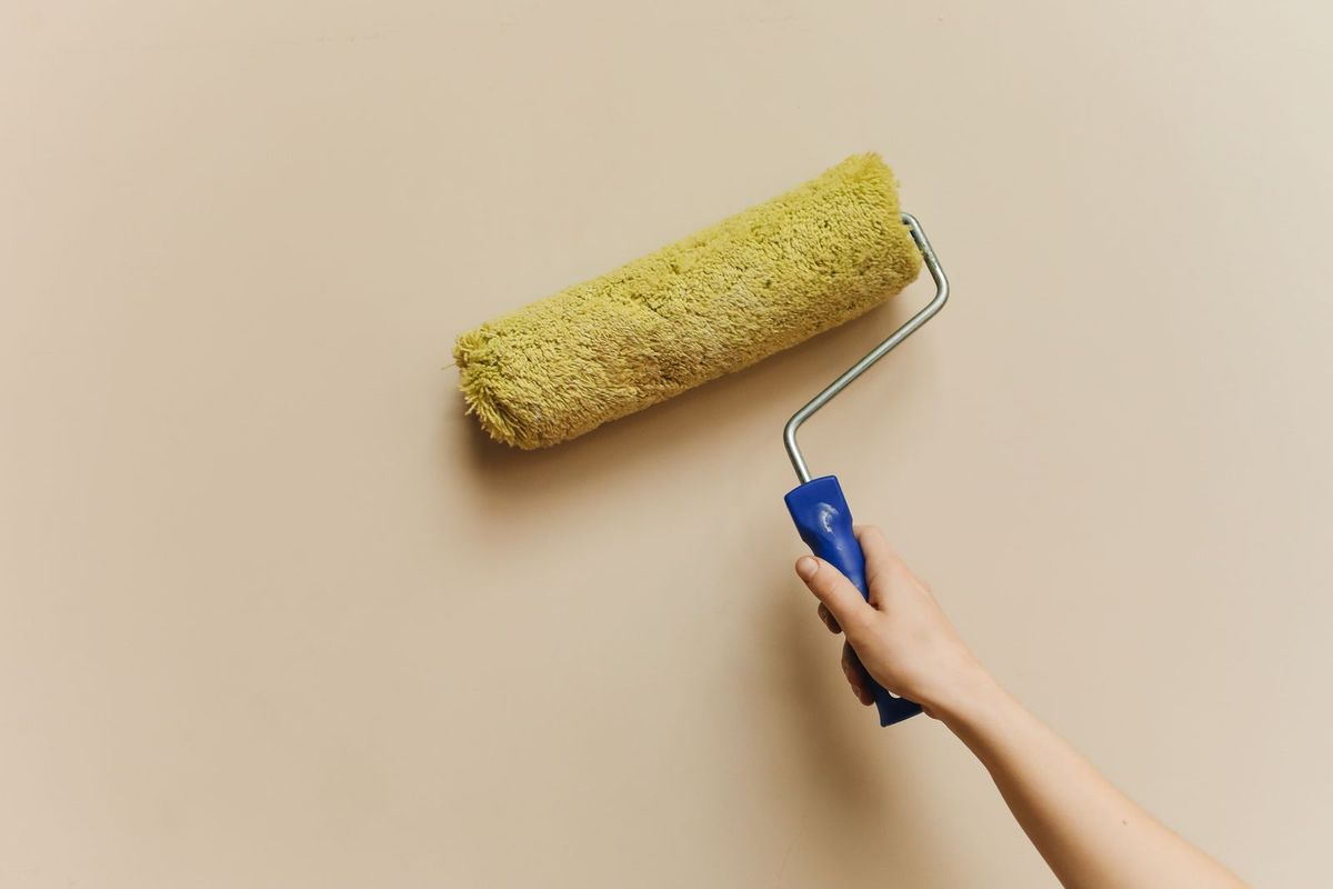 Decorator rolling fresh paint onto a wall