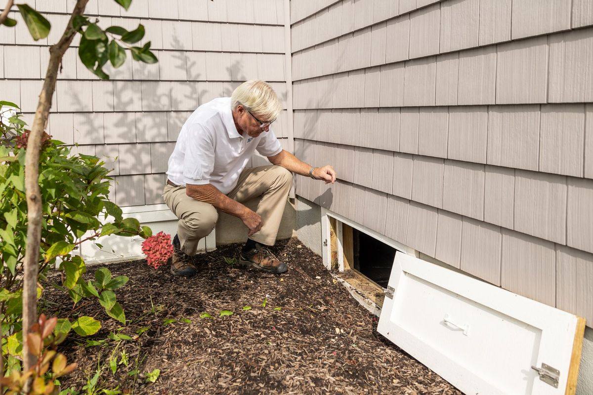 A pest control professional inspecting the exterior of a house