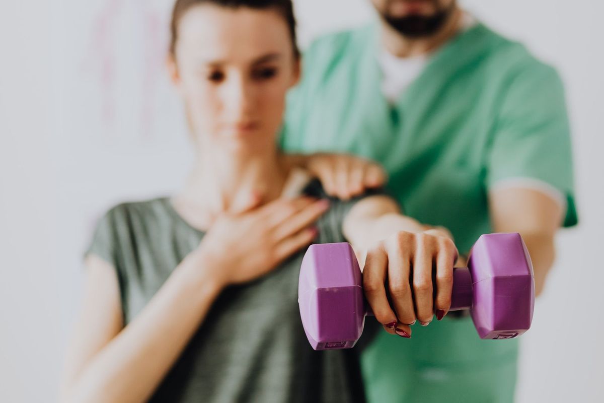 Physiotherapist guiding a patient through a rehabilitation exercise with weights