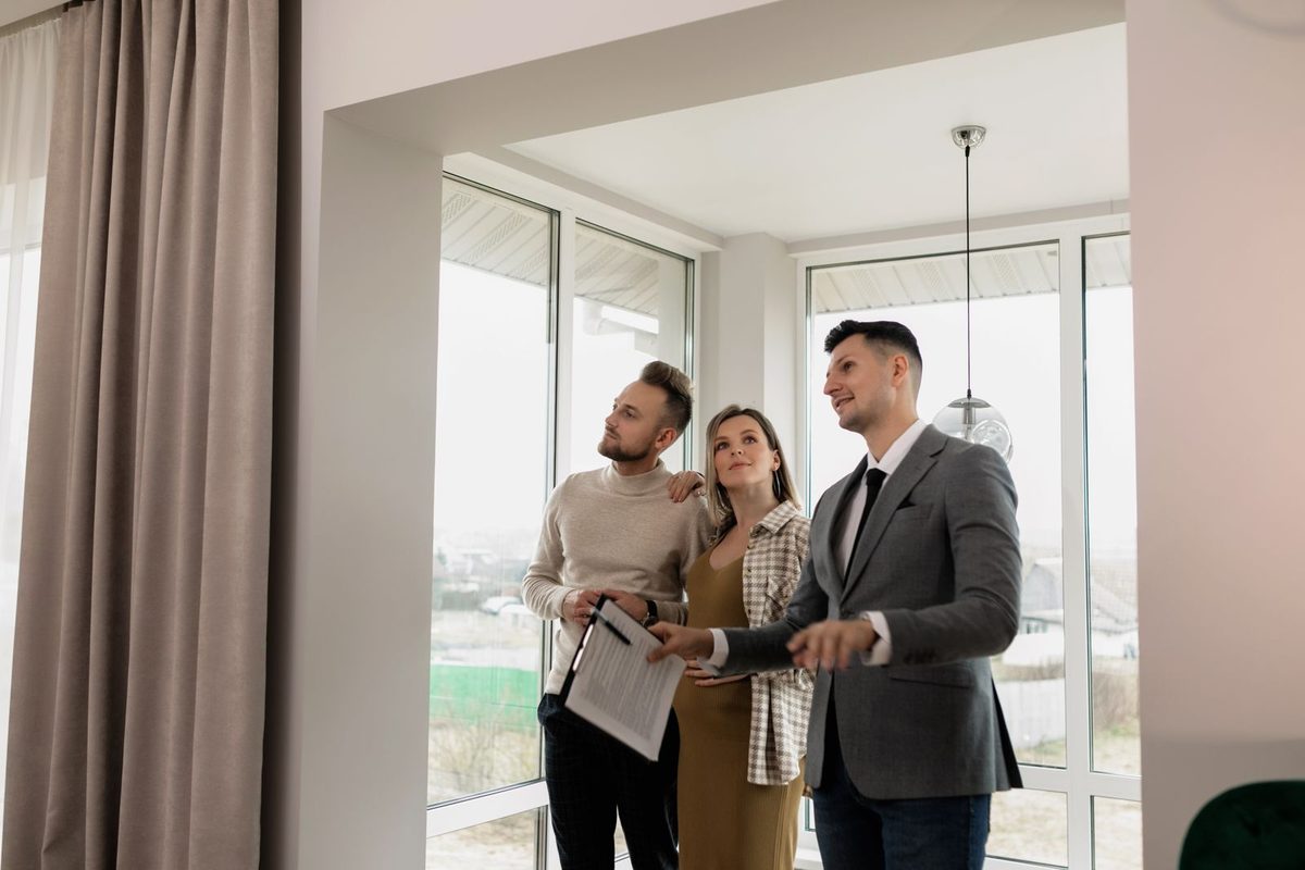 Estate agent showing a couple around a bright apartment