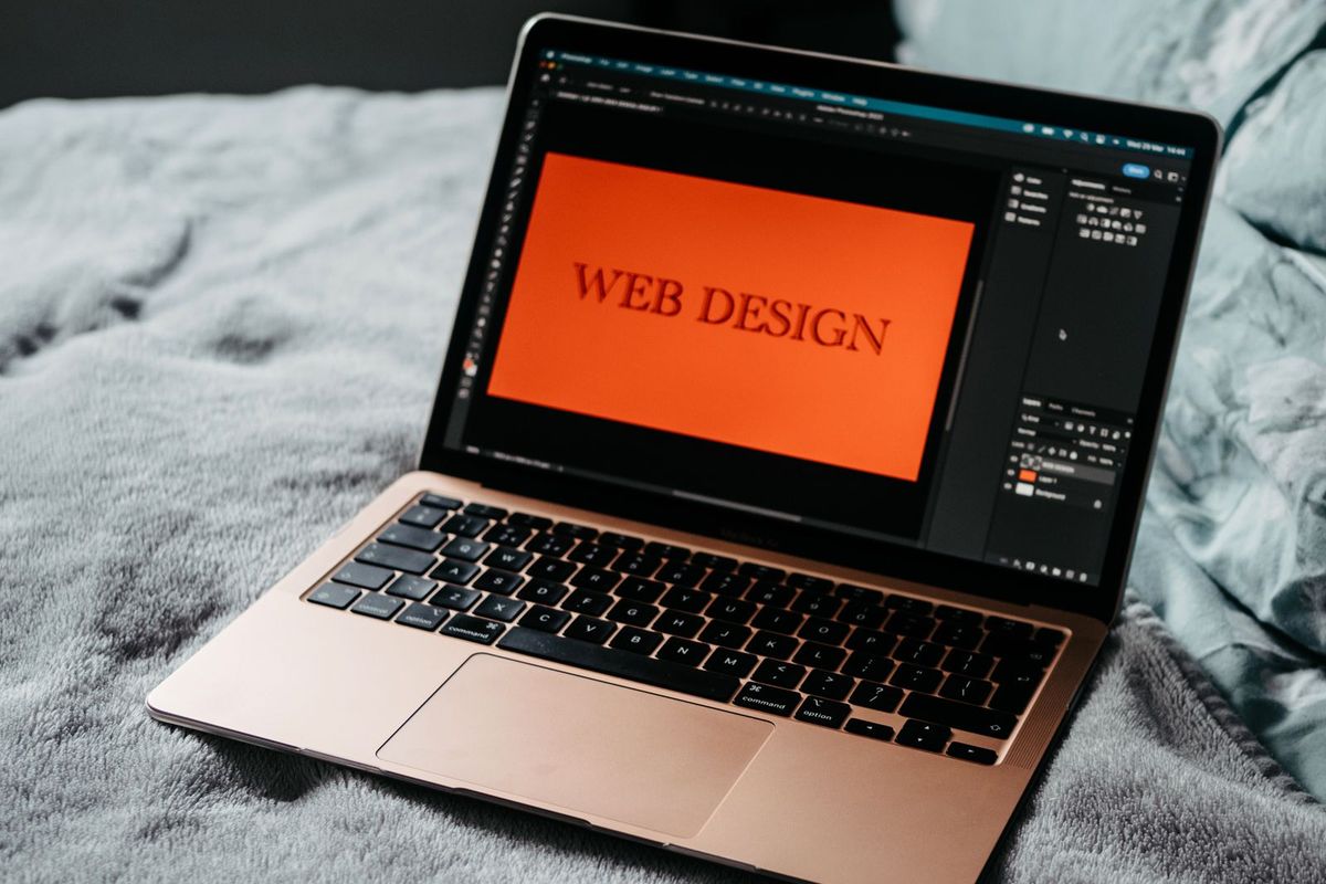 Laptop on a desk showing a web design in progress