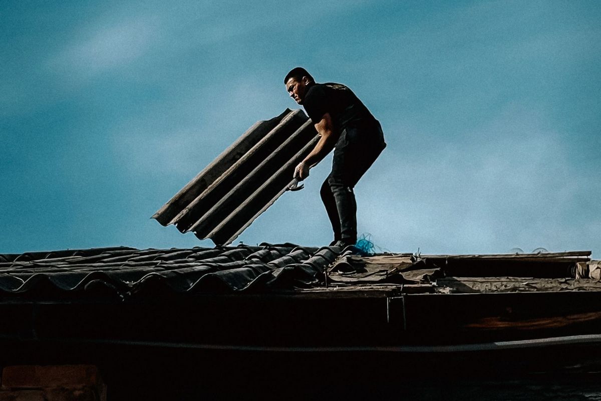 Roofer carrying materials across a roof against a dramatic sky