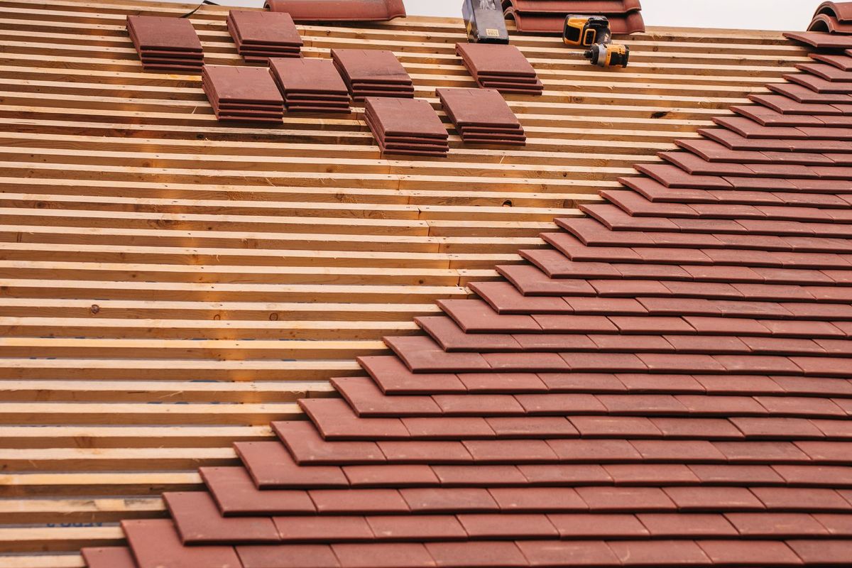 Chiudi-up of roof tiles being inspected, some out of place