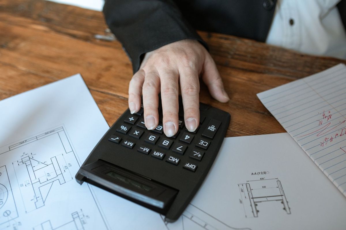 Hand using a calculator over building plans