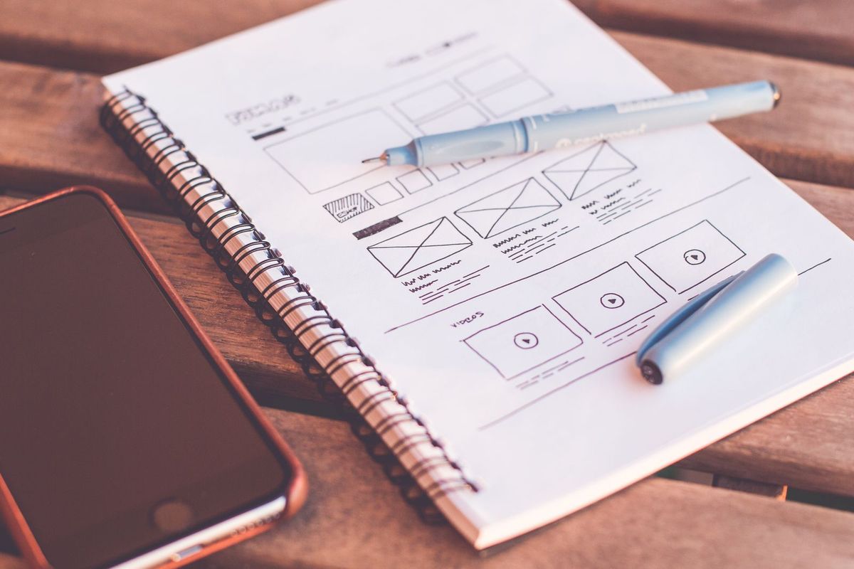 Website layout sketched on paper next to a phone