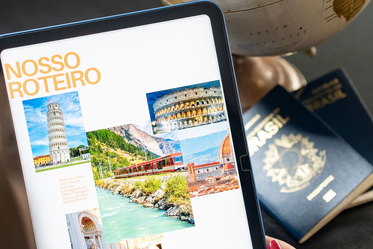 Hands planning a trip with a tablet, brochures and a globe