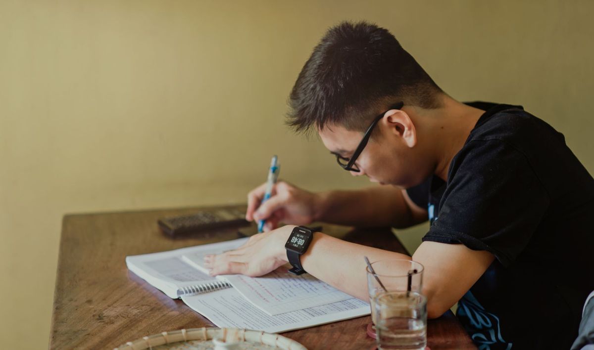 A student concentrating on written work at a desk