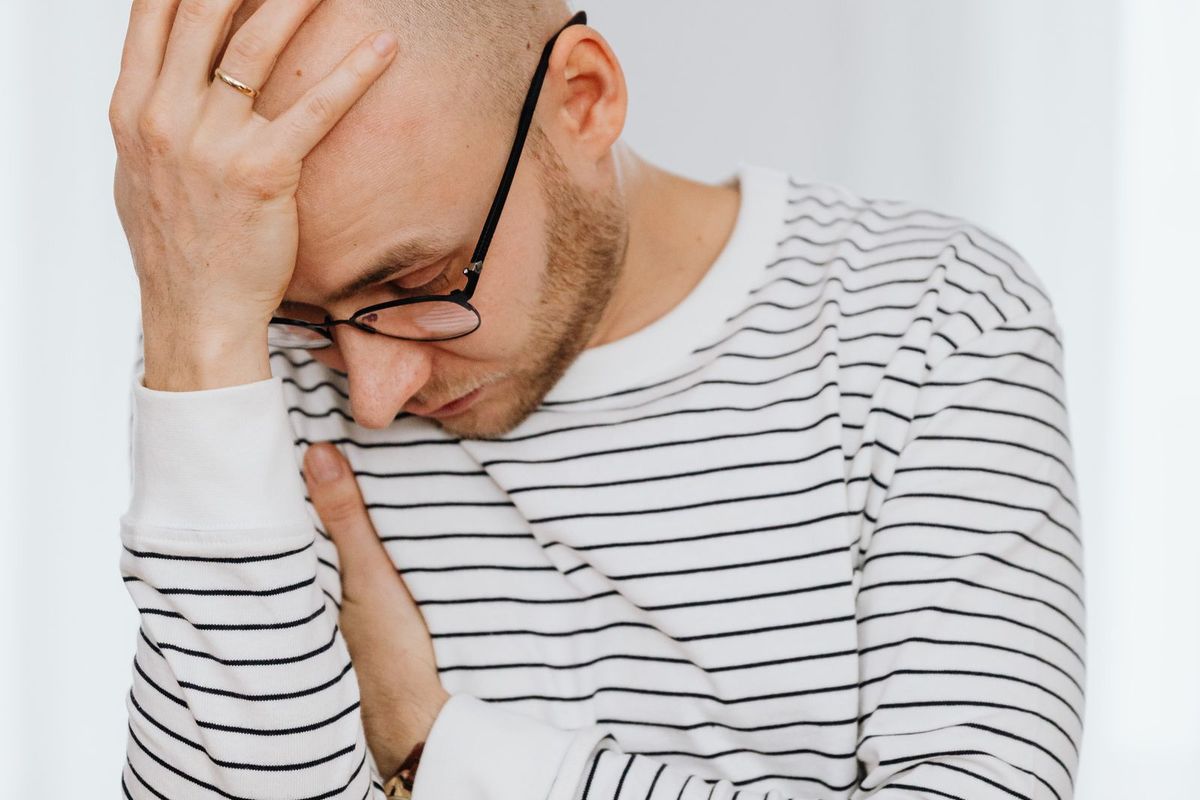 Frustrated person holding their head at a desk