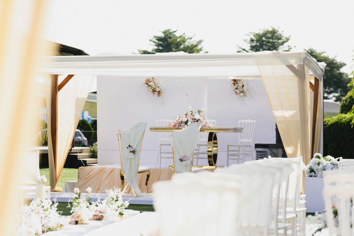 Elegant outdoor wedding ceremony setup with white chairs and floral styling