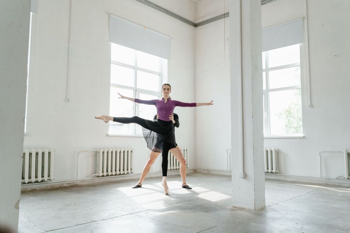 Dancer being guided by an instructor in a dance studio